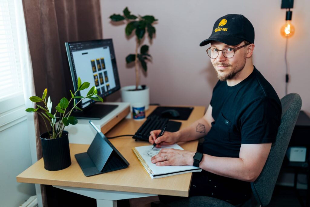 mitä kuvitus maksaa artikkelikuva, kuvassa kuvittaja niklas isberg piirtämässä työpöydän ääressä hymyillen